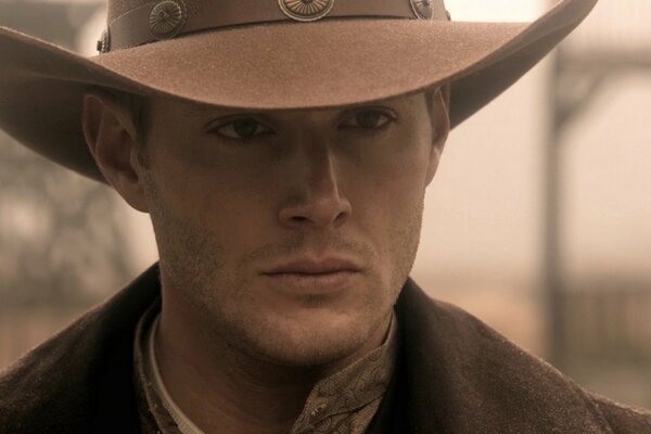 Dean Winchester de pie en la imagen de un vaquero con un sombrero en la cabeza