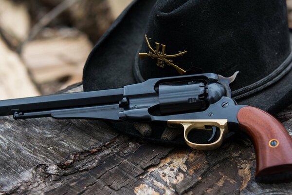 Revolver 1858 et chapeau sur un tronc d arbre sec