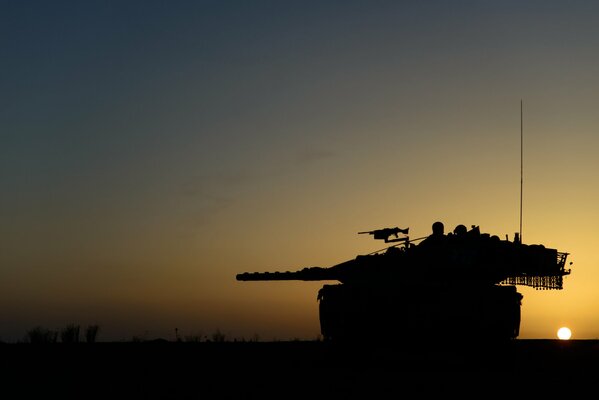 Tanque en la puesta del sol de pie en la estepa