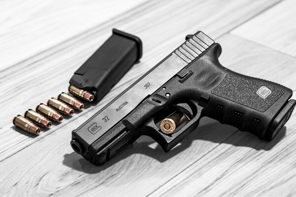 Österreichische Selbstladepistole Glock 32 und Patronen auf grauem Laminat