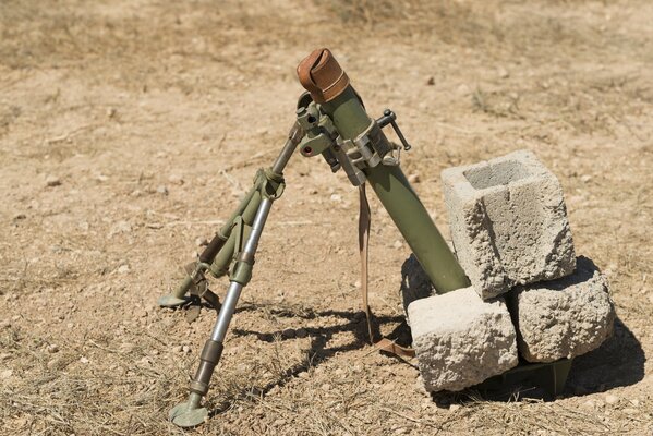 Mounted mortar weapon in a field with stones