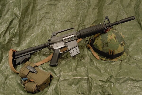 Assault rifle and helmet on a green background