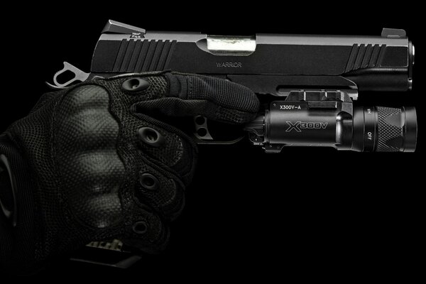 A hand in a black protective glove holds a pistol