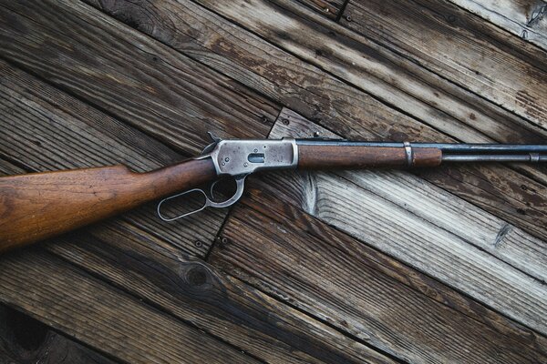 The Winchester Model 92 is lying on wooden boards