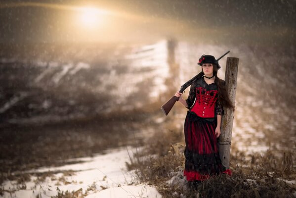 Una donna con una pistola in mano sta tra la neve e l erba