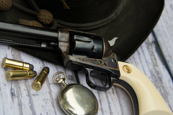 Still life of a revolver and cartridges on a table with a hat