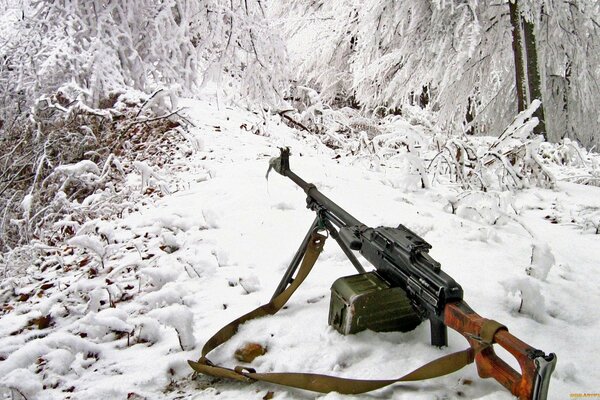 Maschinengewehr vor dem Hintergrund eines mit Schnee bedeckten Bergwegs