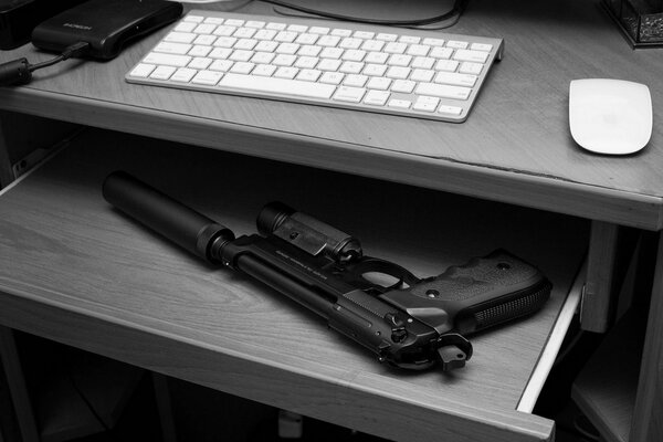 A pistol with a silencer on a shelf in the table