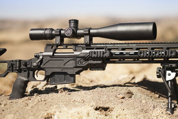 Sniper rifle with optics on the sand