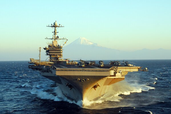 Un portaaviones del tipo Nimitz corta las olas en el fondo de un pico de montaña