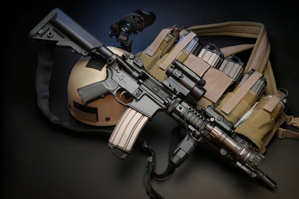 Assault rifle on a dark background with a helmet