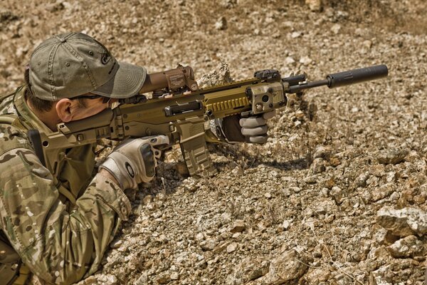 Scharfschütze zielt mit einem Gewehr auf einem Hintergrund von Steinen