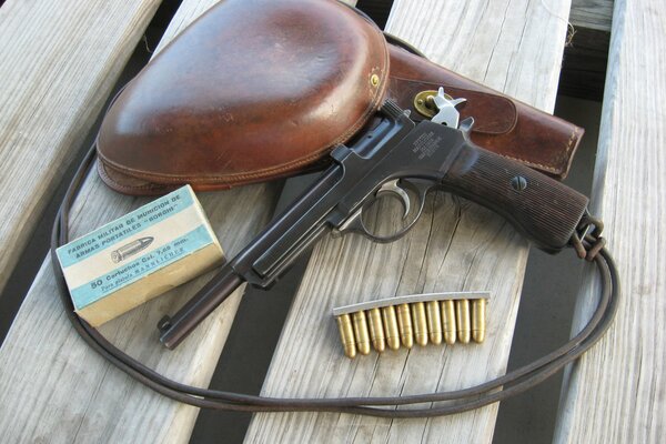 A pistol with a holster and a cartridge clip on a wooden pallet