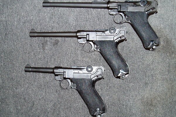 Tres pistolas Luger sobre un fondo gris