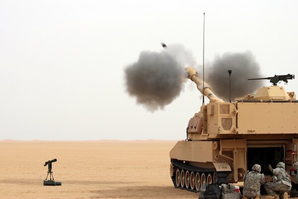 Three soldiers are sitting behind a howitzer