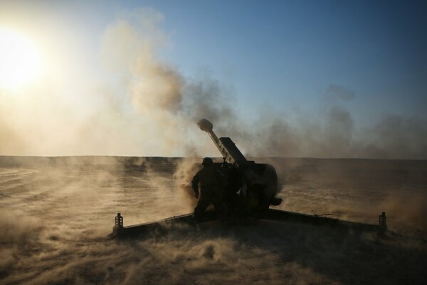 Howitzer in the smoke in the middle of the desert