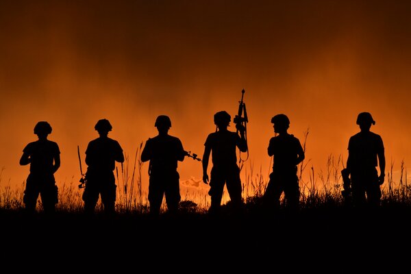 Soldados con armas al atardecer en la hierba