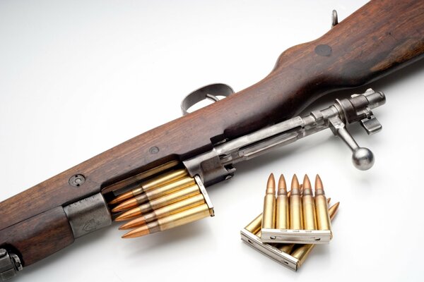 A rifle with a bolt and cartridges on the table