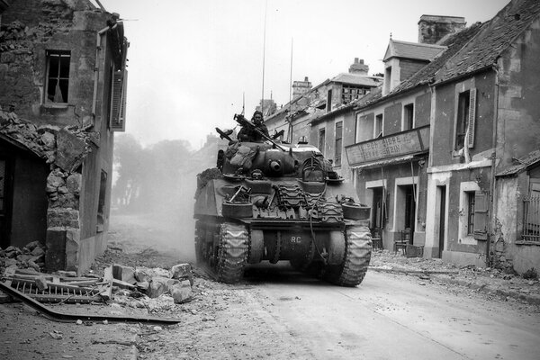 Auf einer zerstörten Straße zwischen den Ruinen von Häusern rollt ein Panzer