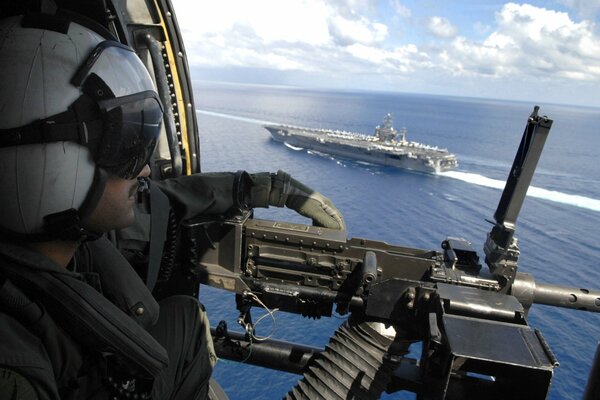 A military machine gun on a helicopter accompanies the ship