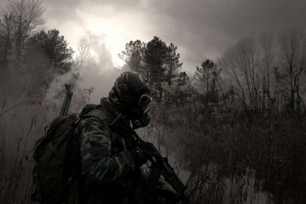 A man in a gas mask with a machine gun in the woods