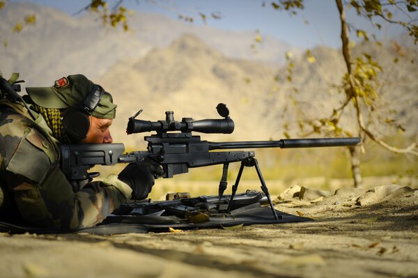 A military man in an ambush looks into the optical sight of his weapon