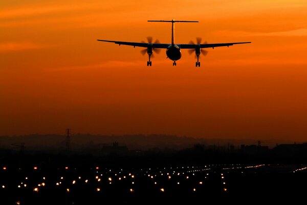 Avion sur fond de ciel coucher de soleil jaune, lumières de la ville de nuit