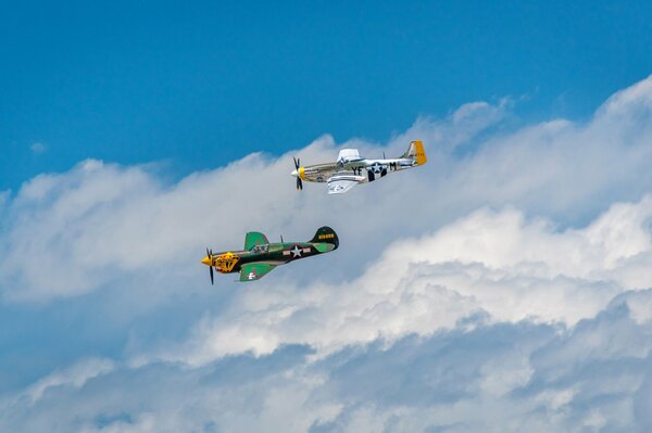 Two military fighter jets are flying in the clouds