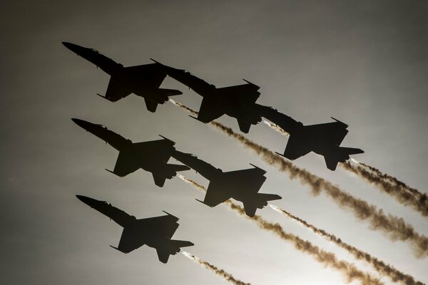 Six fighter jets are flying across the gray sky