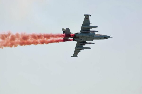 The plane in the sky releases colored smoke. Airshow