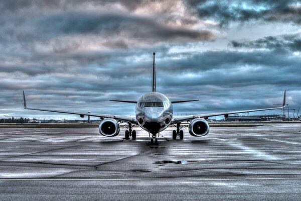 There is a Boeing 737 passenger plane on the runway of the airfield