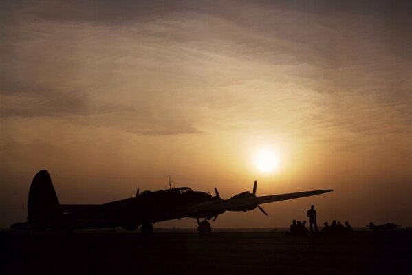 Gruppe von Menschen bei Sonnenuntergang am Flugzeug