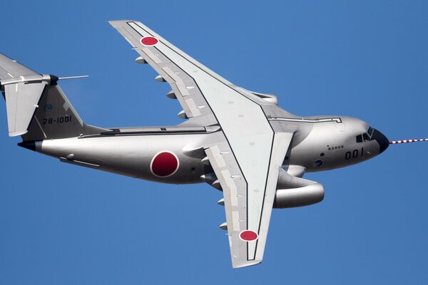 Kawasaki twin-engine military transport aircraft against a cloudless sky