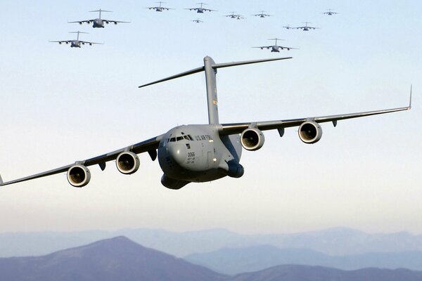 A squadron of heavy aircraft flies over the mountains