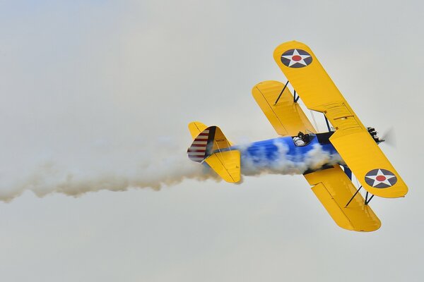 Aereo biplano con fumo che vola in parata