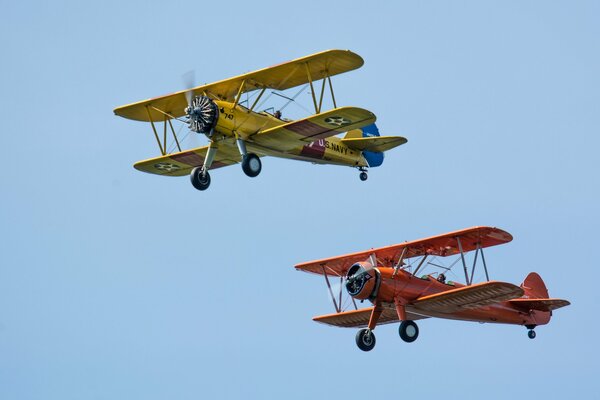 Two retro biplanes on a blue sky background