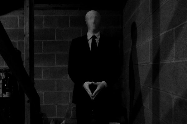 Black and white image of a man without a face in a suit