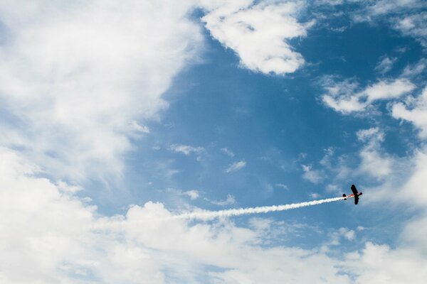 In den Wolken fliegt ein Maisflugzeug und hinterlässt eine Schleppe