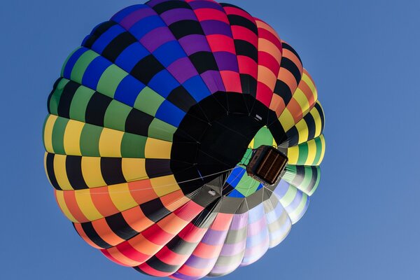 Ein mehrfarbiger Ballon mit einem Korb fliegt in den Himmel