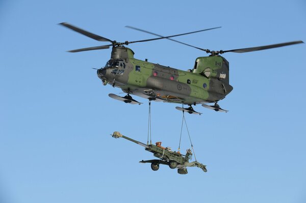 A military transport plane in the sky carrying a howitzer