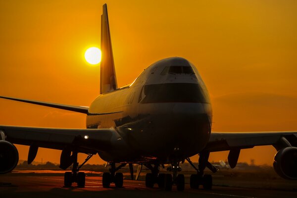 Avión de pasajeros Boeing-747a en el fondo de la puesta de sol