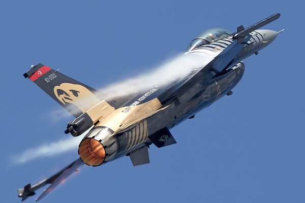 A military plane soars up against the background of a clear blue sky