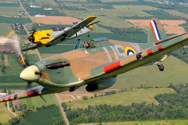 Two planes are flying over beautiful fields