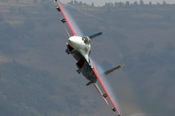 Avion sillonnant dans les nuages sur fond de collines