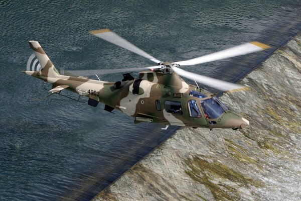 Helicóptero italiano agusta con pintura de camuflaje, volando sobre el río