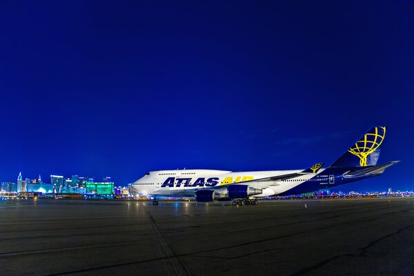 Next to the night lights at the airport in Las Vegas in the USA there is a white and blue plane