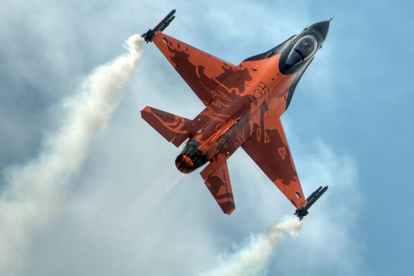 Ein F-16 Fighting Falcon -Mehrzweckjäger in roter Färbung vor einem blauen Himmelshintergrund.