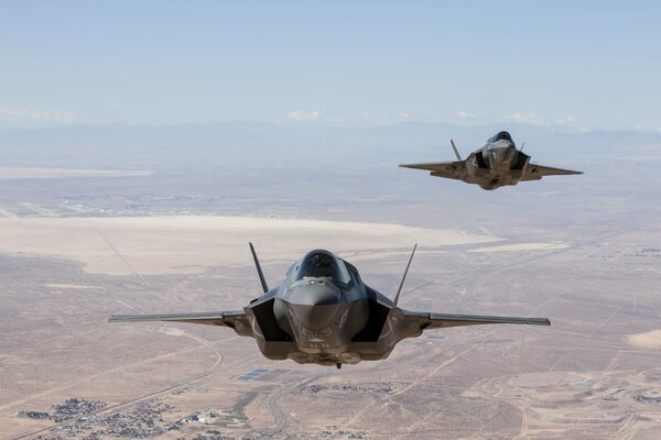 Two military planes in the sky over the desert