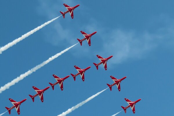 Nine red planes are flying in the sky