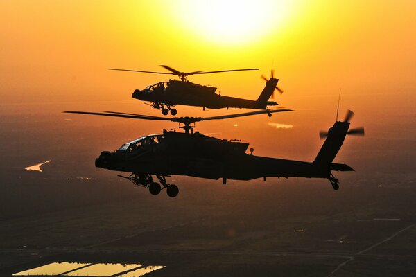 A group of two apache flying against the background of the sun